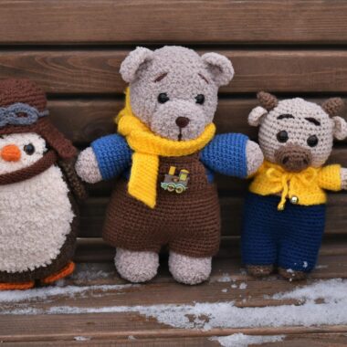 Amigurumi crochet toys placed on a snowy wooden bench. Perfect for winter and craft themes.