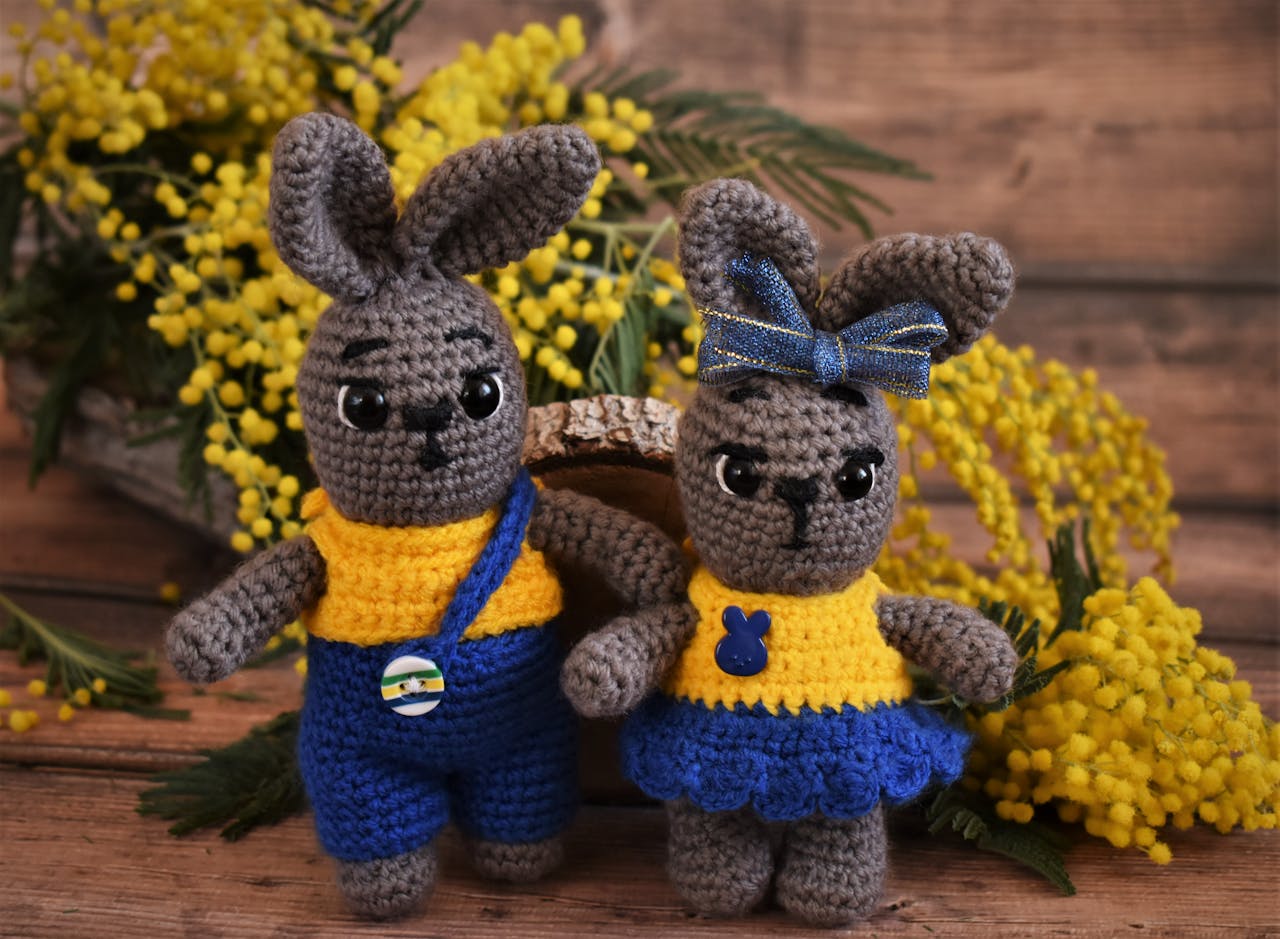 Adorable handmade crochet rabbit toys with yellow flowers in the background.