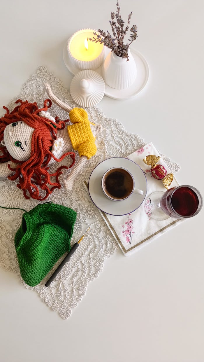 Delightful flat lay featuring a coffee, crochet doll, and decor elements for a cozy setting.